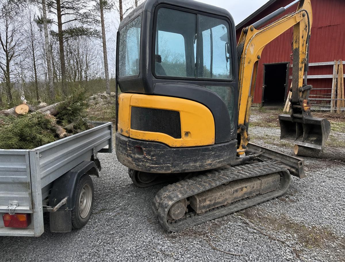 Grävmaskin och släp lastat med ris och stockar